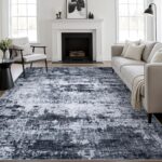 A black 5x7 modern abstract area rug with subtle patterns, laid out in a living room setting.
