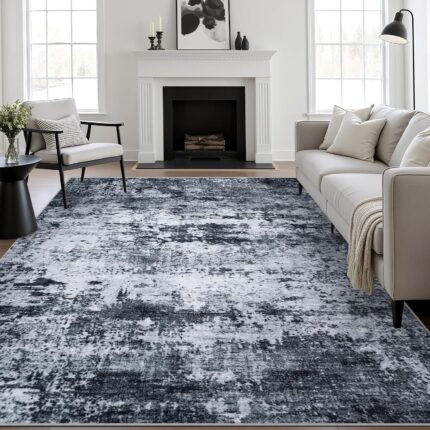 A black 5x7 modern abstract area rug with subtle patterns, laid out in a living room setting.