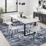 A black 5x7 modern abstract area rug with subtle patterns, laid out in a living room setting.