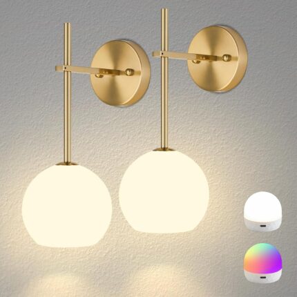 Two gold battery-operated wall sconces with milky white frosted glass shades mounted on a wall, illuminated with a warm glow.