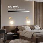 Two gold battery-operated wall sconces with milky white frosted glass shades mounted on a wall, illuminated with a warm glow.