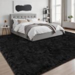A black 8x10 Luxturiy fluffy shag area rug, shown spread out on a floor in a modern living room setting.